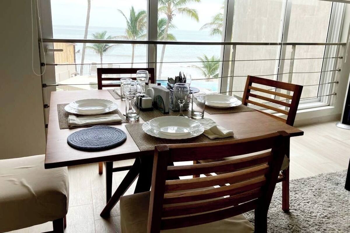 A dining table set for four with a view of the ocean.