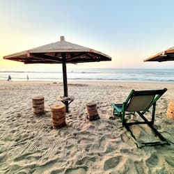 Na praia, areia branca, espreguiçadeiras, guarda-sóis