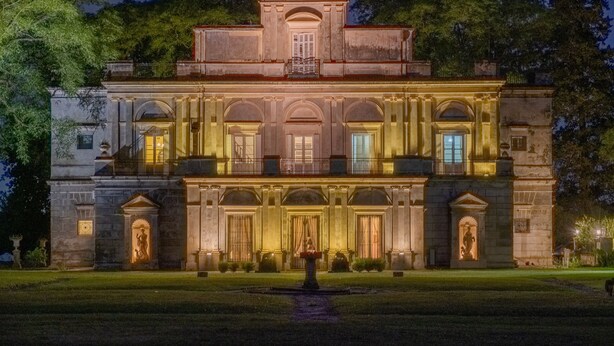 Un edificio grande e histórico con fachada simétrica, amplias ventanas y una entrada central.