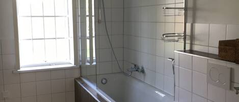 A bathroom with a bathtub, toilet, and a window.