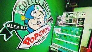 Un mur végétal orné d’une enseigne de café, d’une enseigne de bar à bière et d’un distributeur automatique.