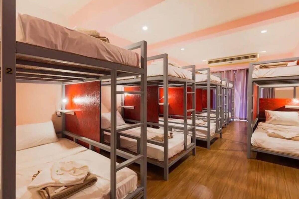Ein Schlafsaalzimmer mit Etagenbetten, Holzboden und einer roten Wand.