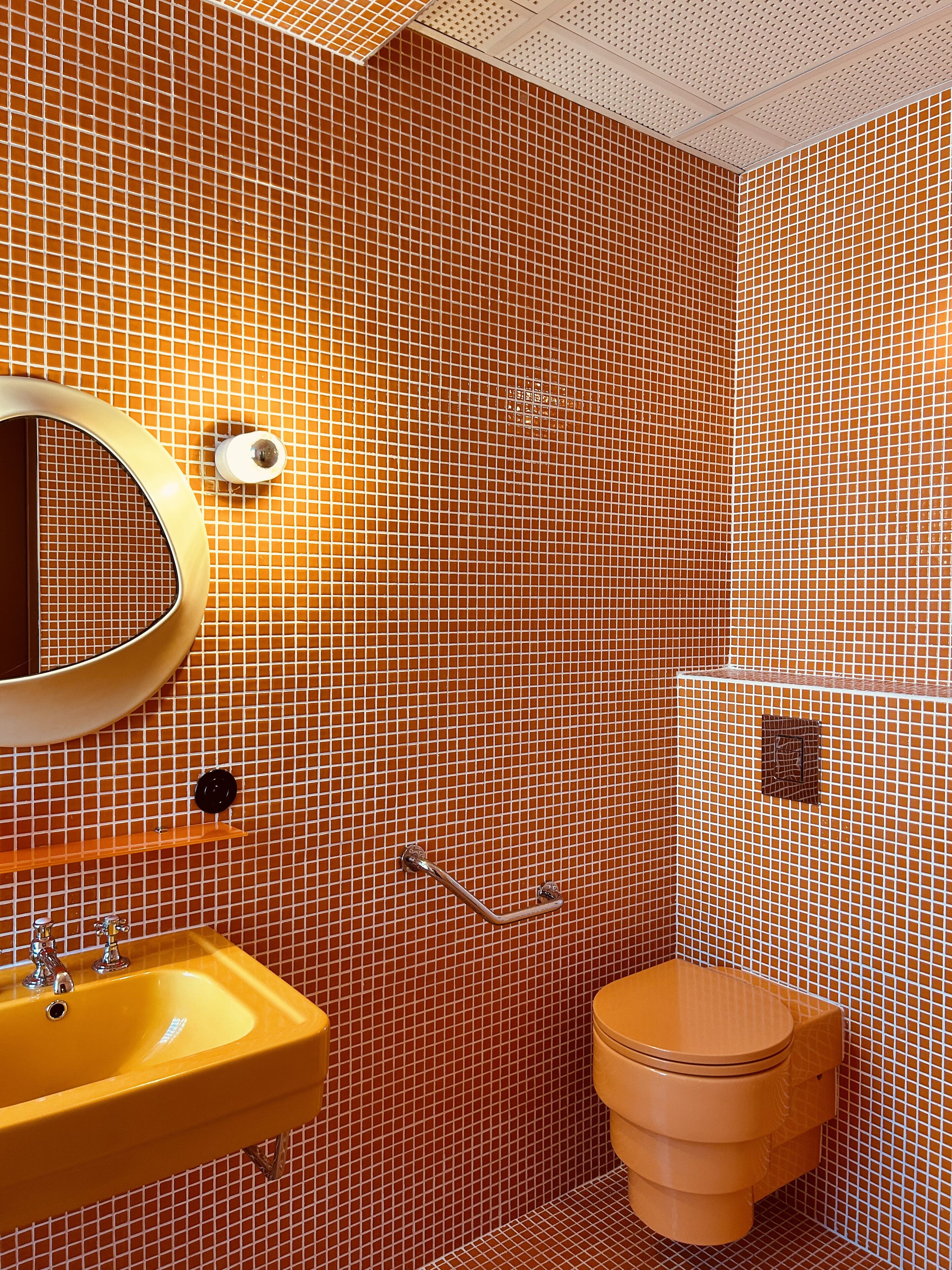 Une salle de bain avec un lavabo jaune, un miroir, des toilettes et un espace douche.
