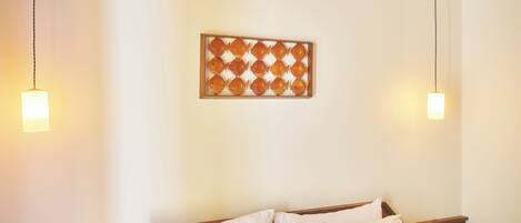 Una habitación de hotel con cabecera de madera, una cama bien hecha con ropa blanca y un panel decorativo en la pared.