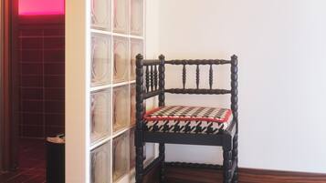 Un coin de pièce avec une chaise en bois, une cloison en verre et un tableau encadré accroché au mur.