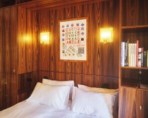 A wooden-paneled room with a bed, two wall-mounted lamps, and a bookshelf. - Hôtel Présent - 200m des Arènes de Arles - Encore Mieux (Arles)