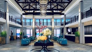 Un hall espacioso con un arreglo floral central, zonas de estar y vistas al mar a través de amplios ventanales.