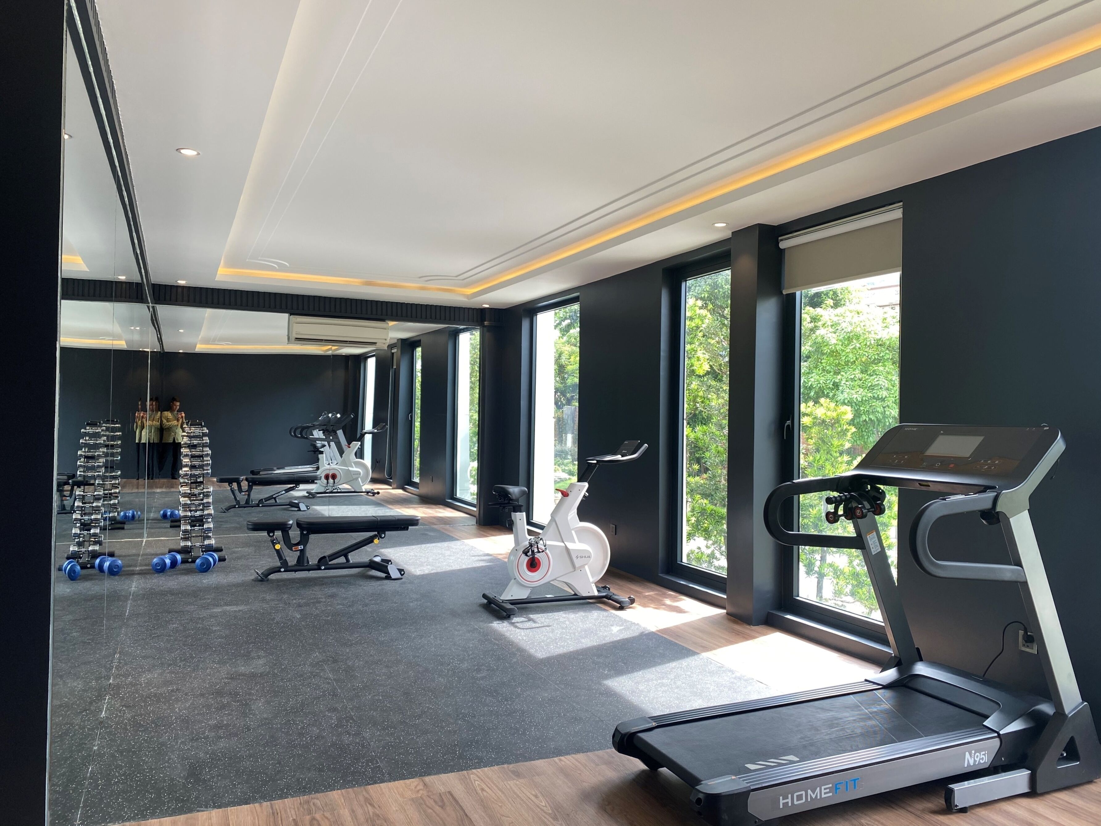 Un gimnasio moderno con cinta de correr, bicicletas estáticas y equipo de levantamiento de pesas.