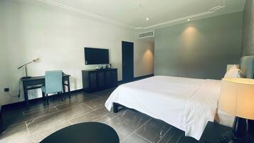 Ein Hotelzimmer mit Bett, Schreibtisch, Stuhl, Fernseher und Lampe.