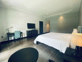 Ein Hotelzimmer mit Bett, Schreibtisch, Stuhl, Fernseher und Lampe.