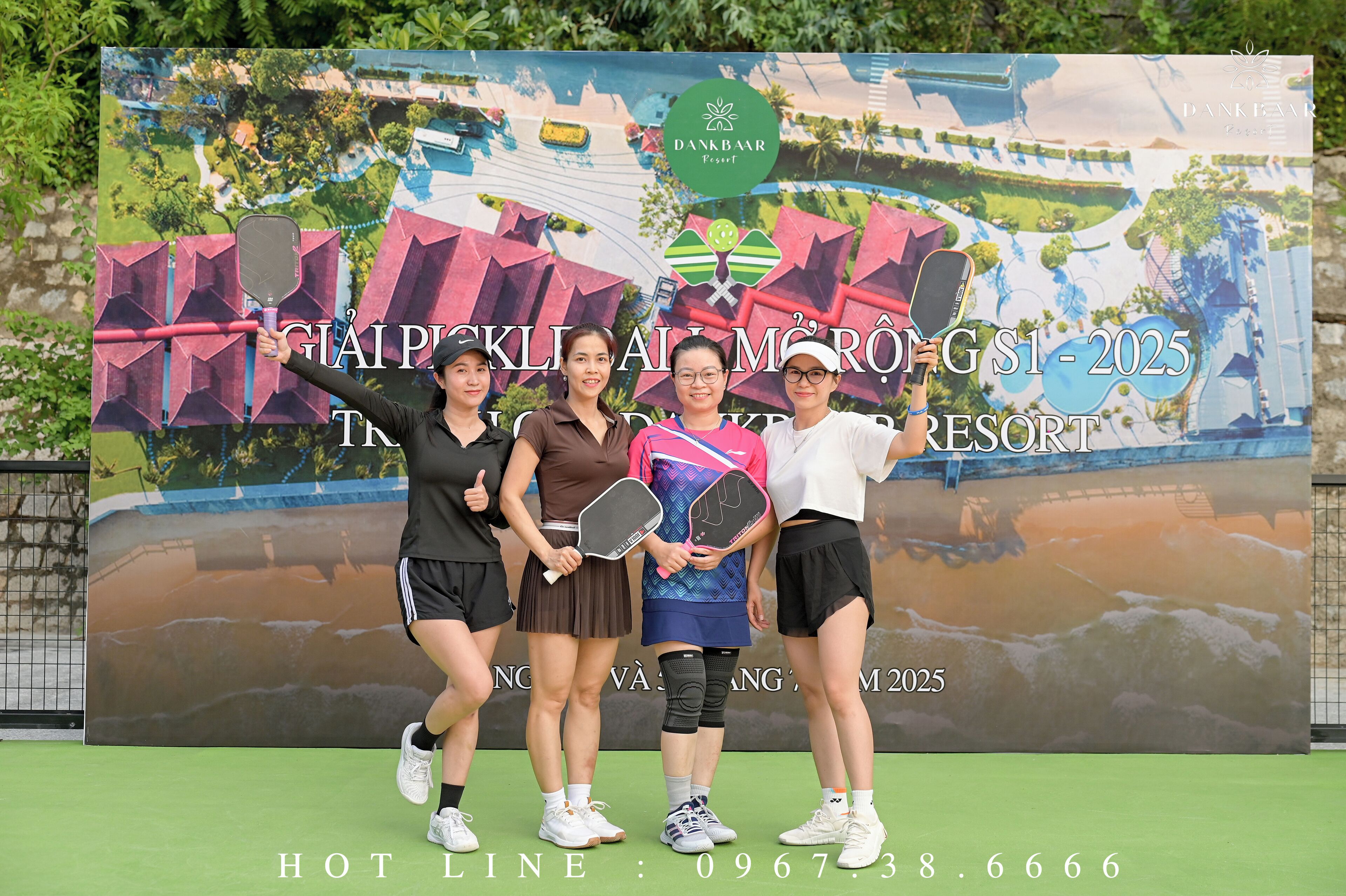 A group of people posing in front of a promotional banner for a resort.