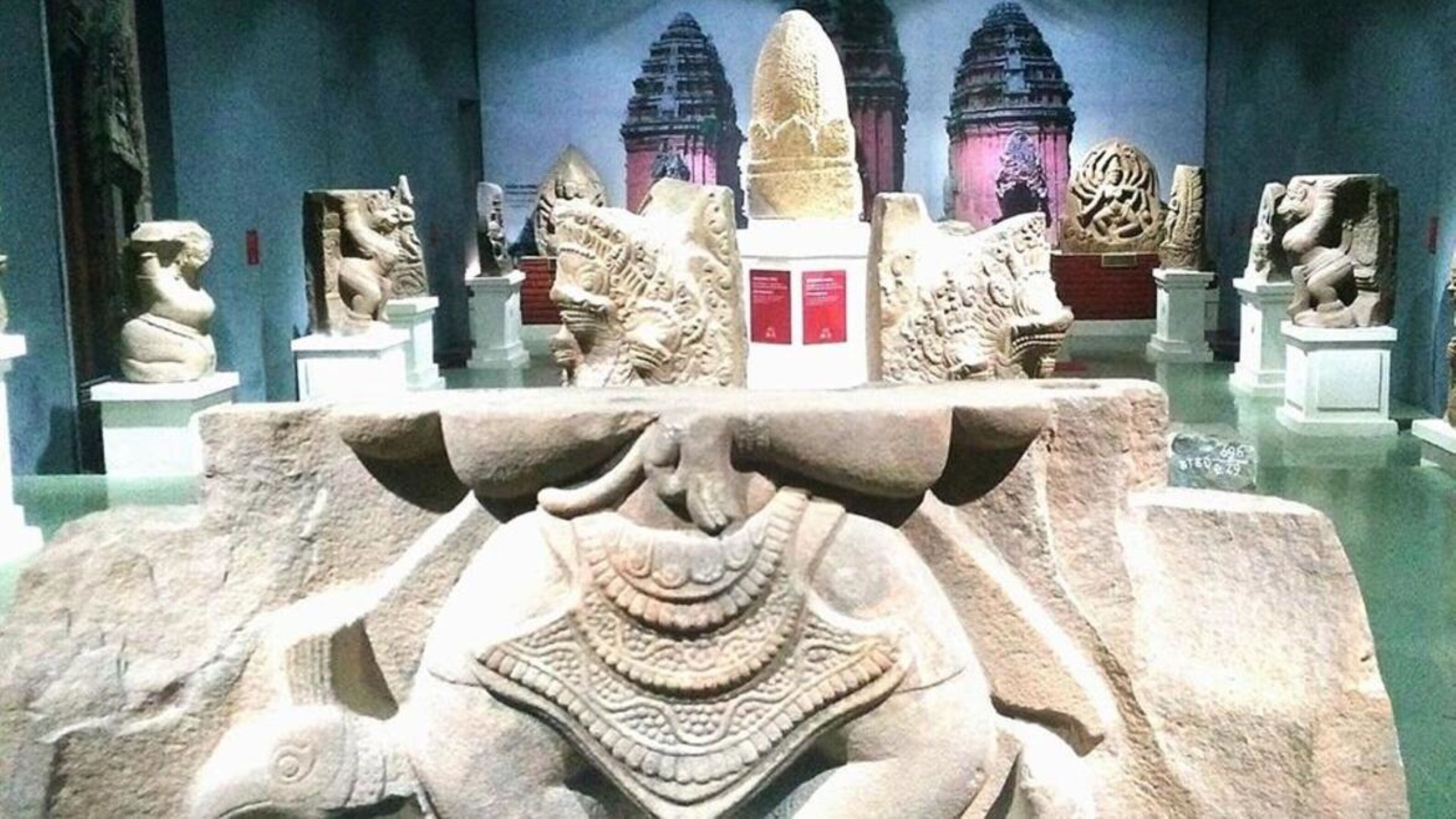 Interno di un museo con sculture in pietra e modelli architettonici.