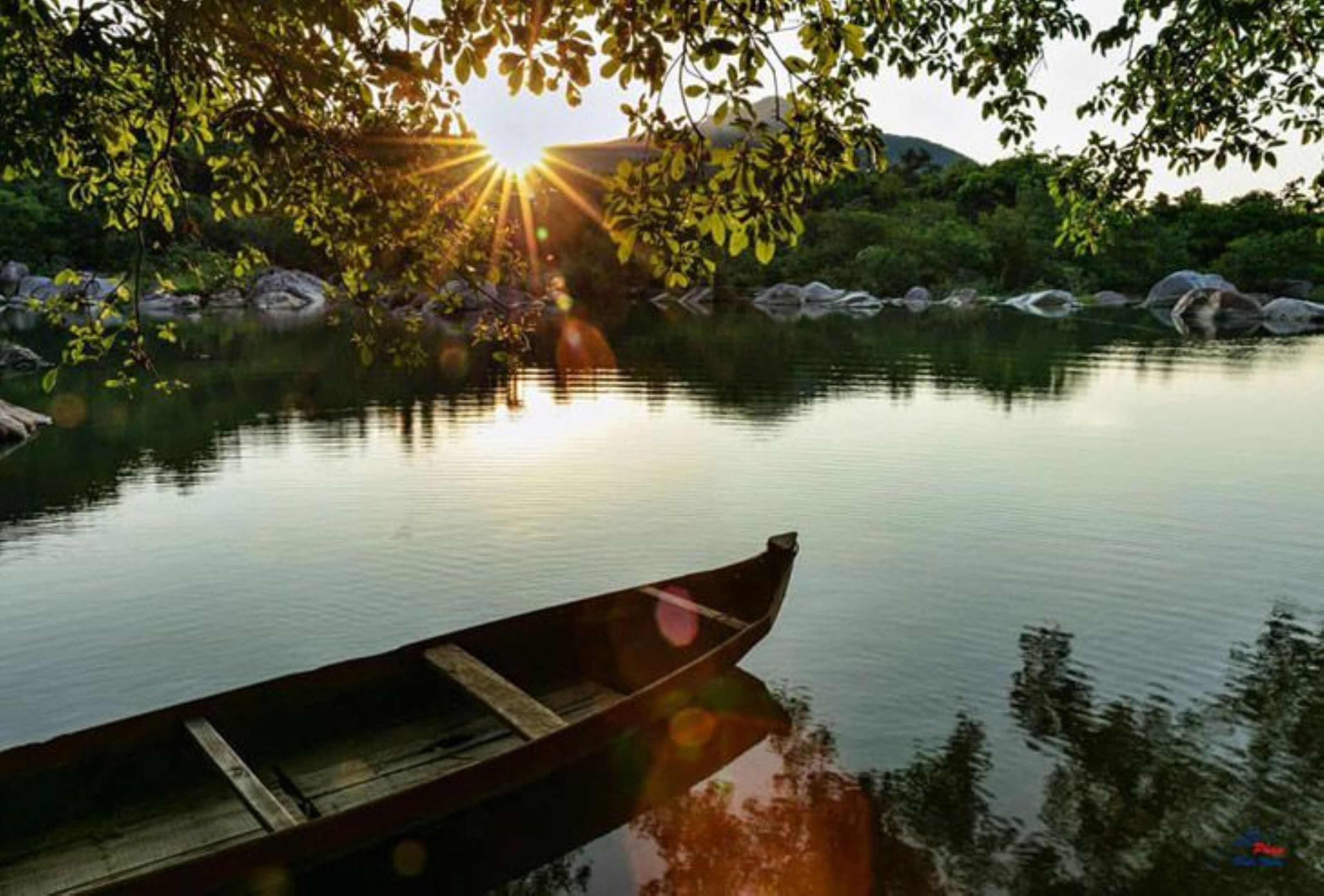 A wooden boat on calm water with sunlight reflecting off the surface.