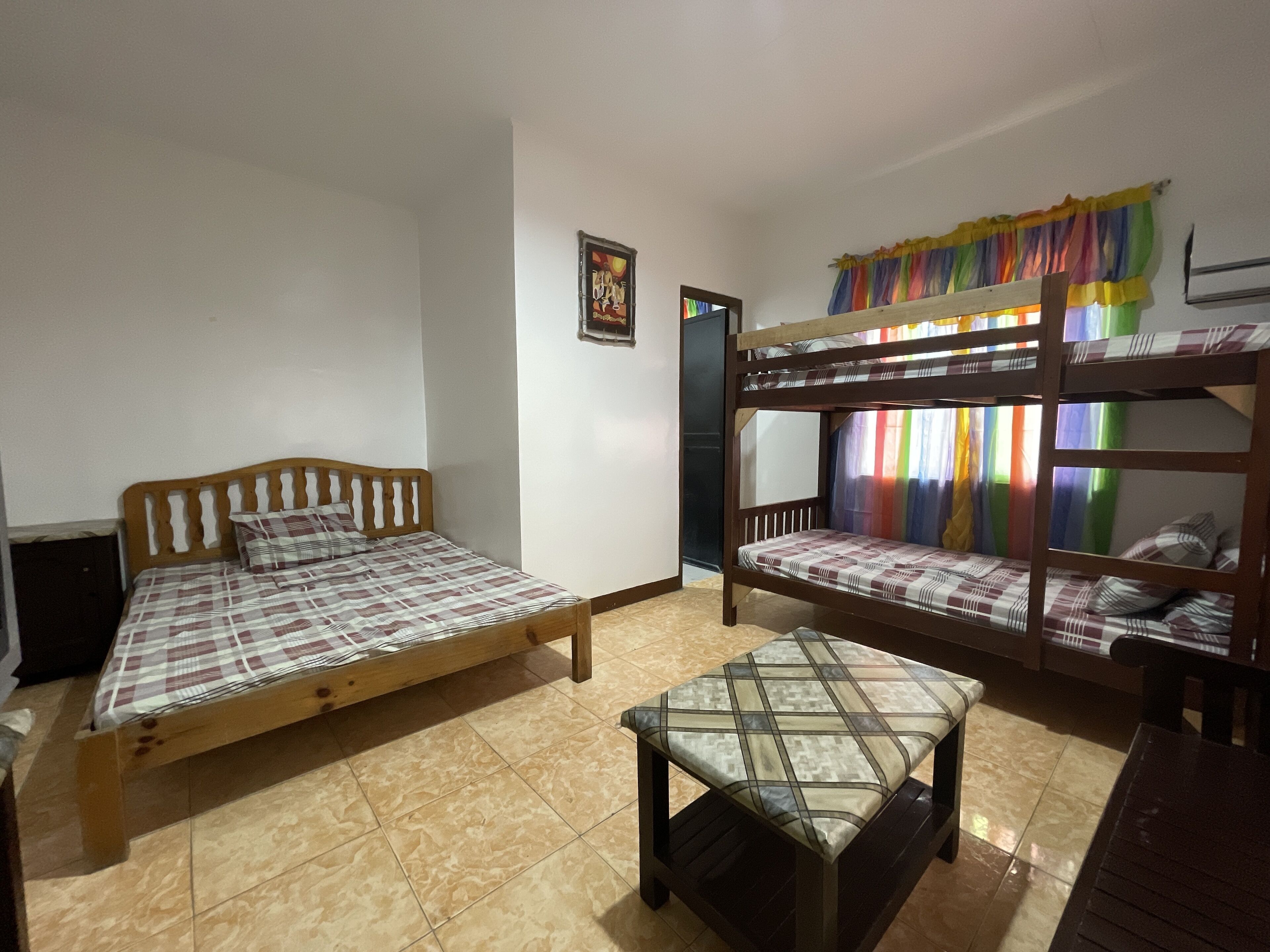 A dormitory room with two beds, a bench, and a door.