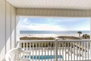 A balcony with a view of the beach and ocean.
