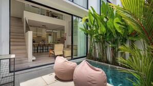 A modern outdoor area with a pool, seating, and indoor access. - Oasis Villa 8 by Betterplace (Canggu)
