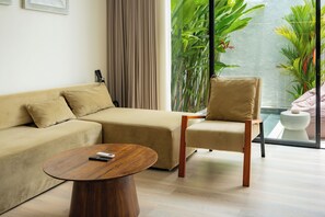 A modern living room with a beige sofa, a wooden coffee table, and a chair with a cushion.