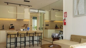 A modern kitchen with a bar area, a sofa, and a round wooden table. - Oasis Villa 8 by Betterplace (Canggu)
