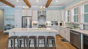 A modern kitchen with a large island, stainless steel appliances, and wooden beams.