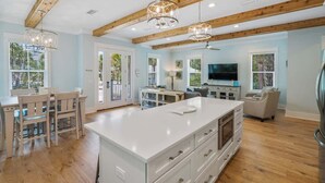 A spacious kitchen with wooden beams, a large island, and a dining area with chairs.