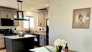 Una cocina moderna con una isla central, una mesa de comedor con bancos y un ventilador de techo.