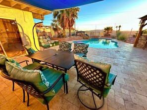 Un patio exterior con piscina, zona de estar y un área cubierta.