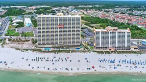 Ein Hochhotel mit Pool und Blick auf den Strand, umgeben von Wohngebiet.