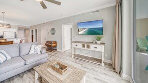 Ein modernes Wohnzimmer mit einem grauen Sofa, einem Holztisch und einem Fernseher auf einer weißen Unterhaltungsanlage.