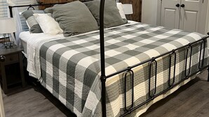 Un letto a baldacchino con copripiumino a quadri, un comodino con una lampada e un pavimento in legno.