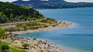 Une plage avec des gens, un bateau et un paysage vallonné en arrière-plan.