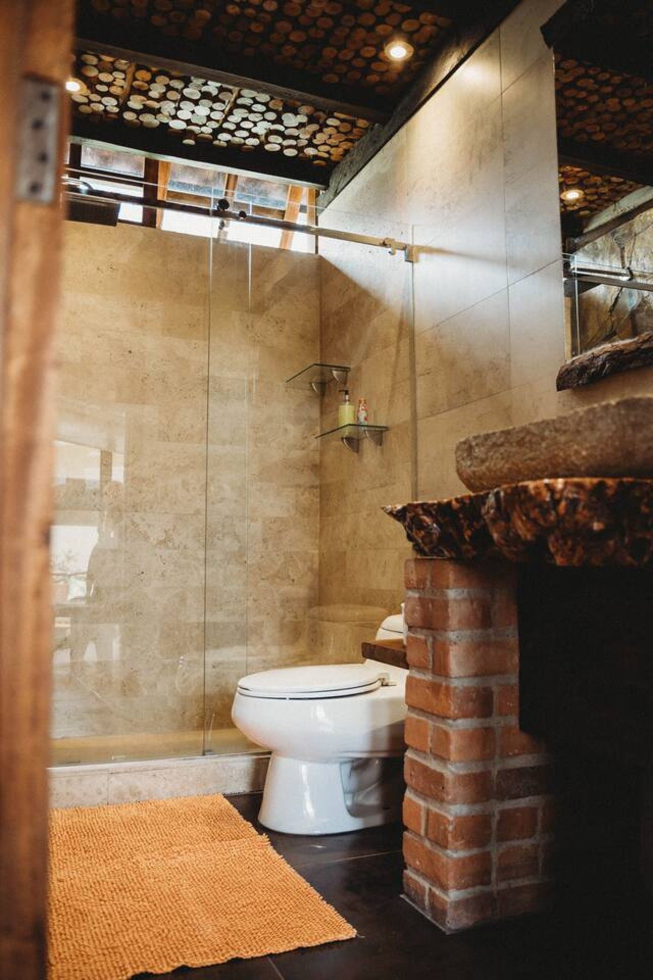 Ein Badezimmer mit Dusche, Toilette und einem Waschbecken aus Ziegeln.