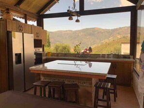Una cucina con un'isola grande, sgabelli di legno e vista su un paesaggio montuoso.