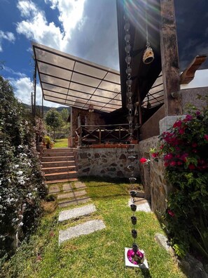 A covered outdoor area with a stone wall, a staircase leading up, and a row of hanging lights. - Villa Nathalie, jaccuzzi, king size bed+hammock (Chican, Paute)