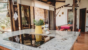A kitchen with a granite countertop, a yellow pitcher with flowers, and a dining area in the background. - Villa Nathalie -Cheerful Rustic House (Chican, Paute)