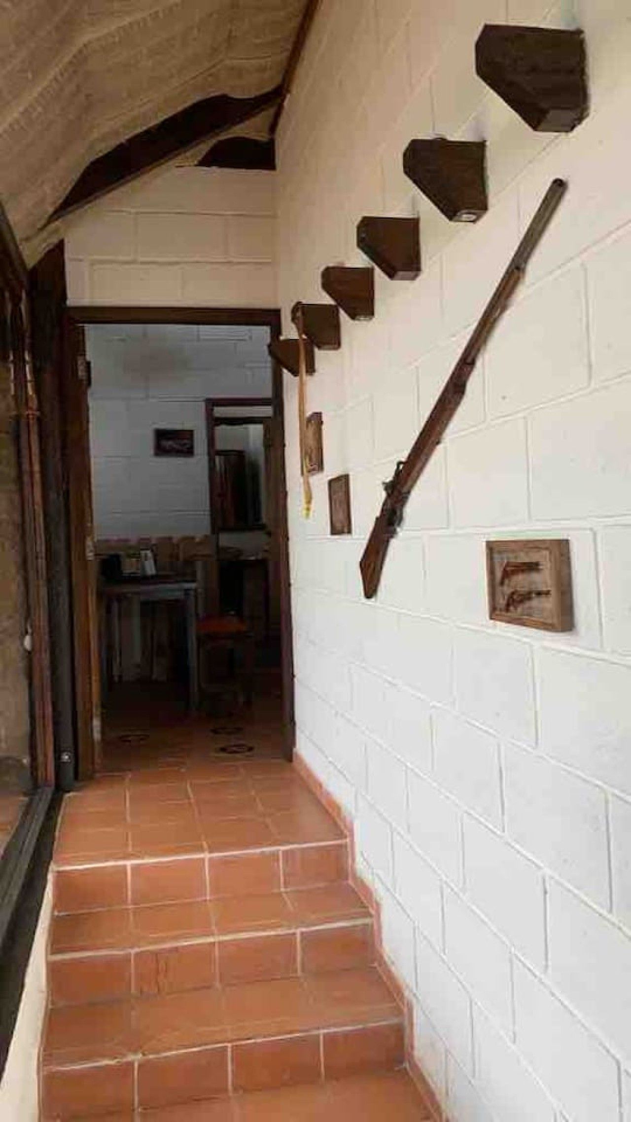 A corridor with a tiled floor leading to a room with a white brick wall.