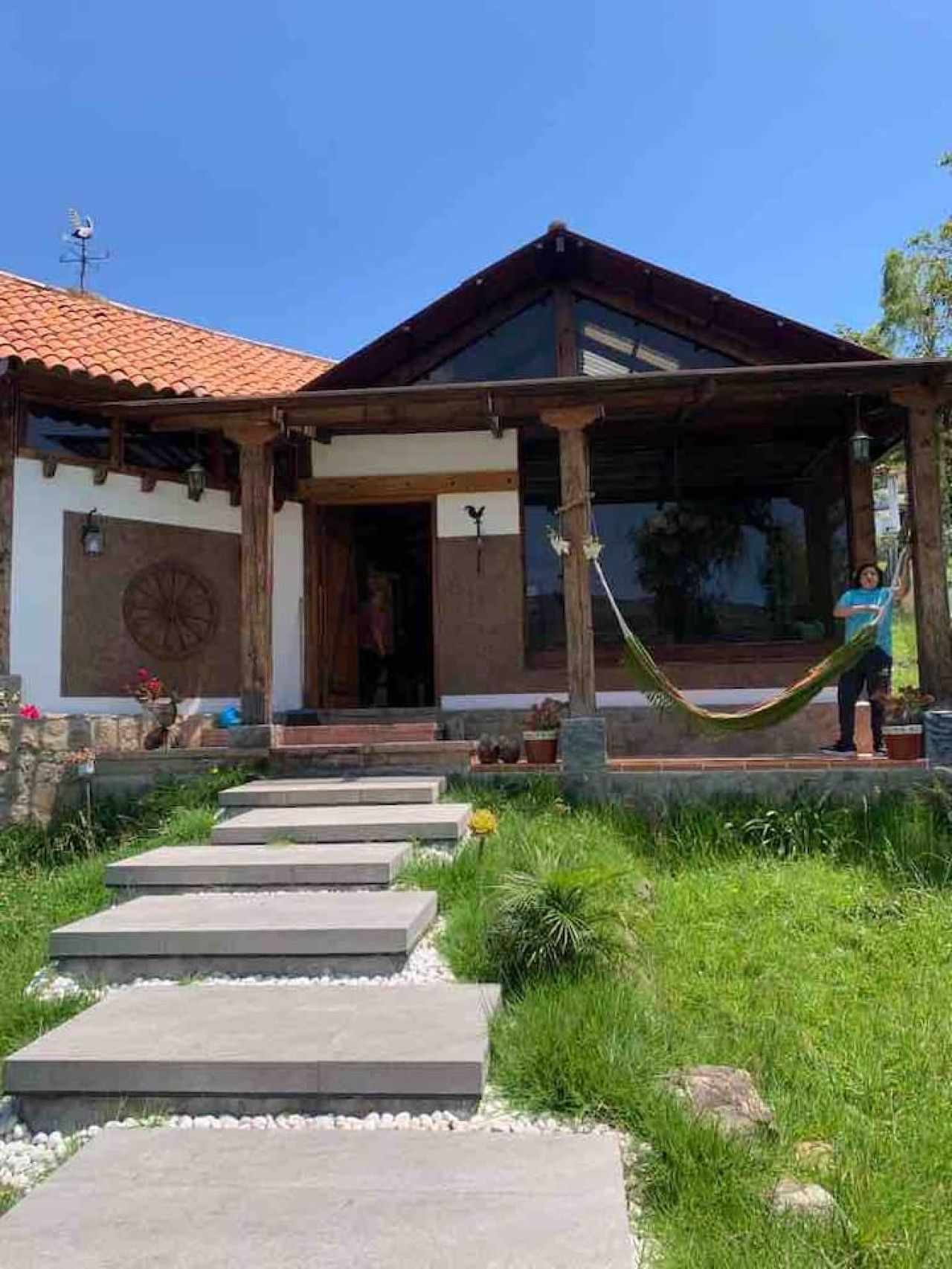 Une maison dotée d’un porche abrité, d’une grande fenêtre et d’un chemin de pierre menant à l’entrée.