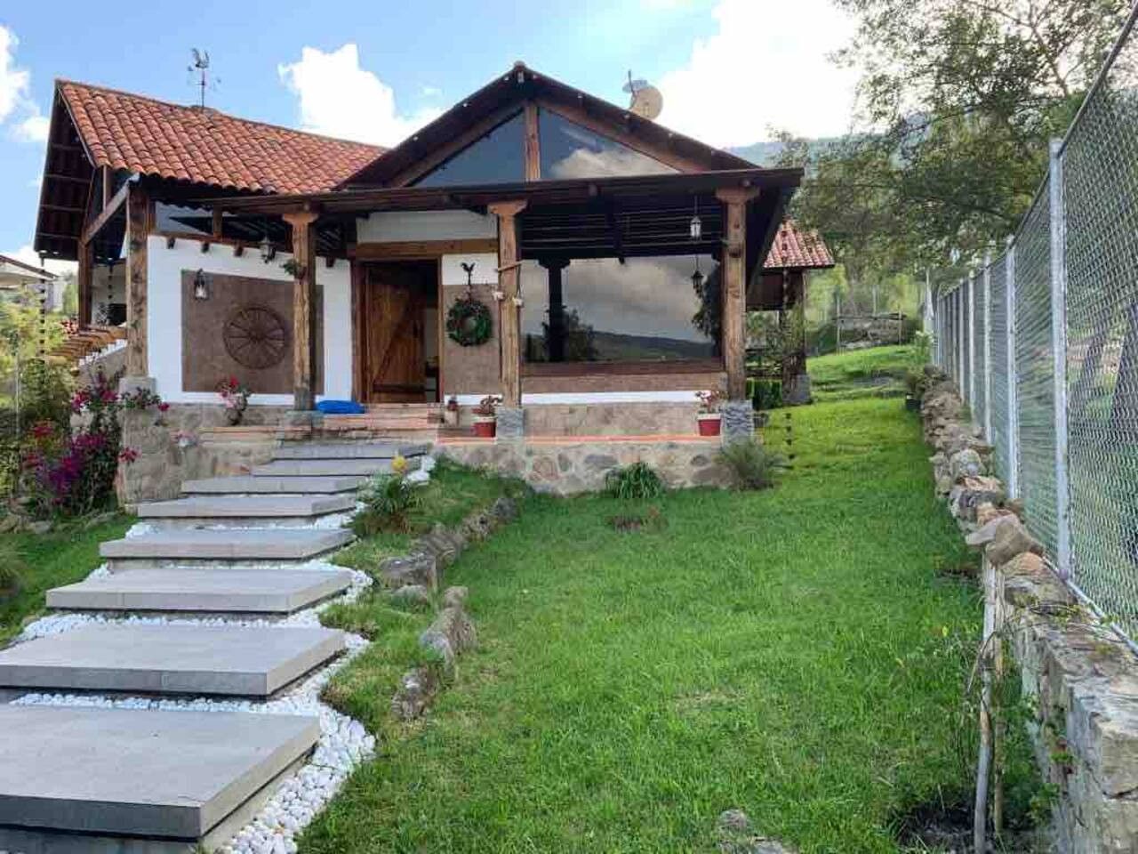 A house with a stone pathway leading to the entrance, a fenced yard, and a clear sky.