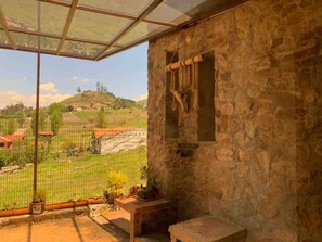 A stone-walled room with a view of a rural landscape, a window with a metal frame, and a small bench. - Villa Nathalie, jaccuzzi, king size bed+hammock (Chican, Paute)