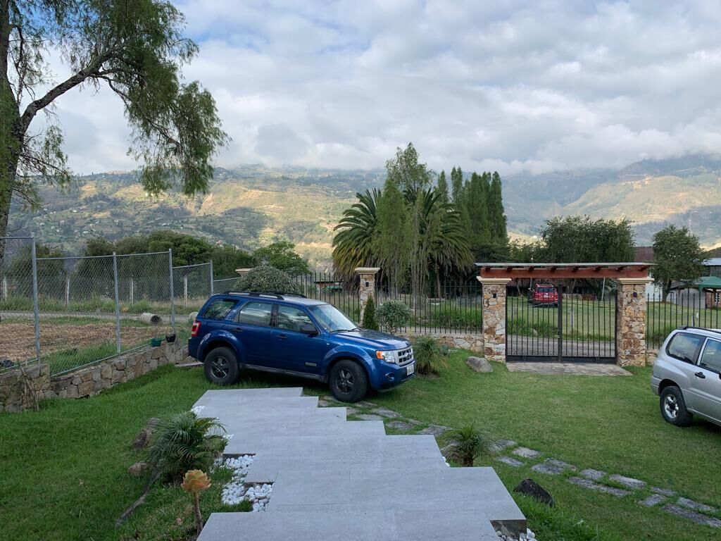 Un SUV azul estacionado en una entrada con un muro de piedra y una puerta metálica.