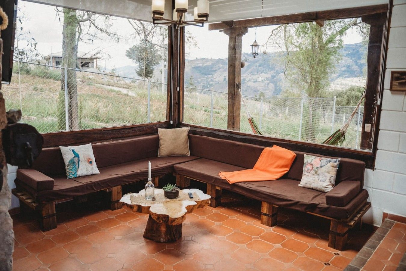A cozy seating area with a wooden bench and a stone coffee table, large windows with a view of the outdoors.