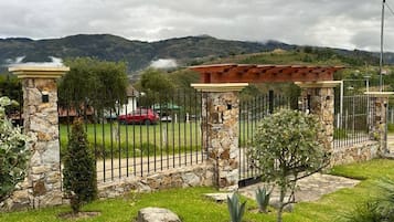 Una proprietà recintata con pilastri in pietra, un vialetto lastricato e, sullo sfondo, una macchina rossa.