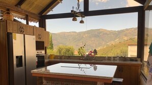 A kitchen with a large island, wooden cabinets, and a view of the mountains. - Villa Nathalie -Cheerful Rustic House (Chican, Paute)