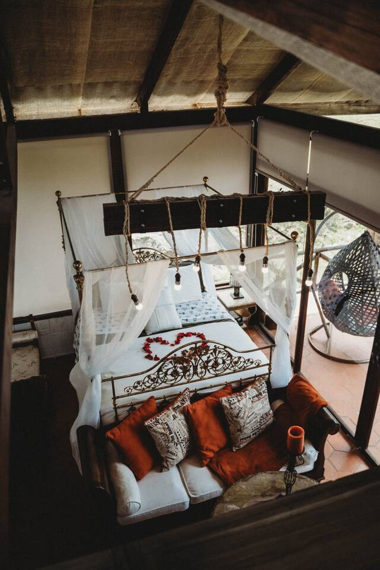 Una cama con dosel, un sillón colgante y vistas al exterior.