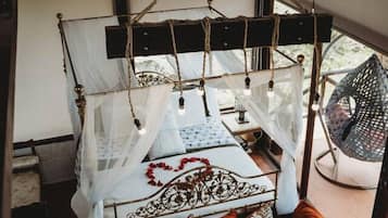 Una cama con dosel, un sillón colgante y vistas al exterior.