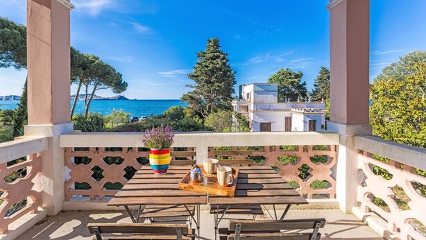 A balcony with a view of the sea, a wooden table with a tray, and a colorful vase. - Villino Rosa – mit Garten und Meerblick (Portoferraio)