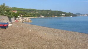 A pebbled beach with a parked car and boats, a clear sky, and a hilly landscape in the background. - Villino Rosa – mit Garten und Meerblick (Portoferraio)