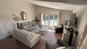 Una sala de estar con sofá, sillón, mesa de centro y mueble para televisión.