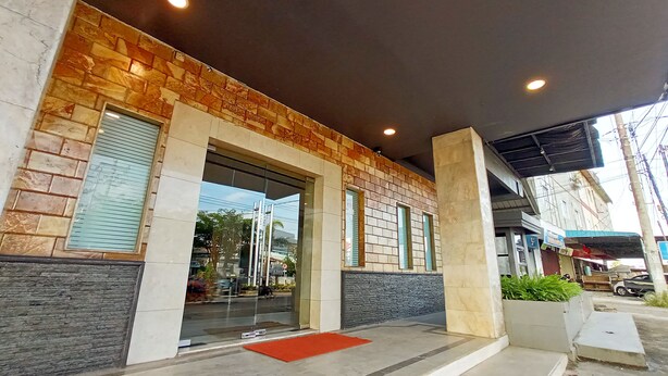 A building with a stone facade, large glass doors, and a red mat at the entrance. - Kita Hotel (Tanjung Pinang)