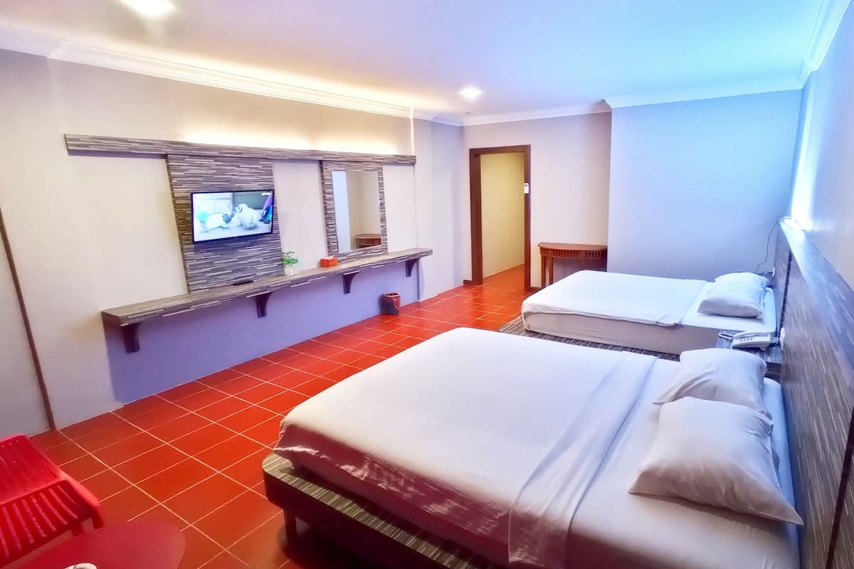 Hotellihuone, jossa on kaksi sänkyä, hyllyllä oleva televisio ja punainen tuoli.