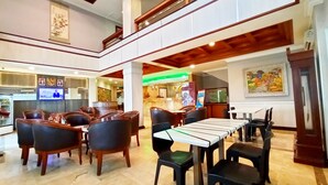A spacious lobby with a high ceiling, a reception area, and a dining area with tables and chairs. - Kita Hotel (Tanjung Pinang)